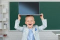 Happy school boy holding laptop on head, studying online e-learning use internet. Education and knowledge modern Royalty Free Stock Photo