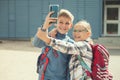 Happy school children playing and making selfies with cellphone at schoolyard after lessons Royalty Free Stock Photo