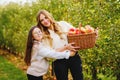 Happy school girl and beautiful mother with red apples in organic orchard. Happy woman and kid daughter picking ripe Royalty Free Stock Photo