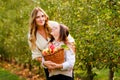 Happy school girl and beautiful mother with red apples in organic orchard. Happy woman and kid daughter picking ripe Royalty Free Stock Photo