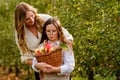 Happy school girl and beautiful mother with red apples in organic orchard. Happy woman and kid daughter picking ripe Royalty Free Stock Photo