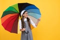 happy school girl in glasses. teen child under colorful parasol pointing finegr. Royalty Free Stock Photo