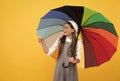 happy school girl in glasses. teen child under colorful parasol pointing finegr. Royalty Free Stock Photo