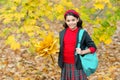 Happy school girl handful of yellow maple leaves in park, school time