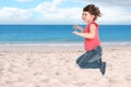 School girl jumping on beach near sea, space for text. Summer holidays Royalty Free Stock Photo