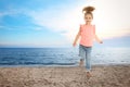 School girl jumping on beach near sea, space for text. Summer holidays Royalty Free Stock Photo