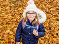 Happy school girl with a wide smile lies on a carpet of red and yellow leaves in an autumn park. Little smiling child Royalty Free Stock Photo