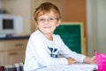 Happy school kid boy with glasses at home making homework Royalty Free Stock Photo