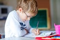 Happy school kid boy with glasses at home making homework Royalty Free Stock Photo