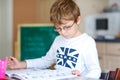 Happy school kid boy with glasses at home making homework Royalty Free Stock Photo