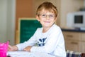 Happy school kid boy with glasses at home making homework Royalty Free Stock Photo