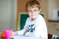 Happy school kid boy with glasses at home making homework Royalty Free Stock Photo