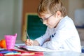 Happy school kid boy with glasses at home making homework Royalty Free Stock Photo