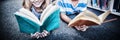 Happy school kids lying on floor and reading a book in library Royalty Free Stock Photo