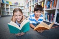 Happy school kids lying on floor and reading a book in library Royalty Free Stock Photo