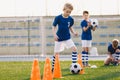 Young boys kicking soccer ball on training. Children practicing football on school grass pitch Royalty Free Stock Photo