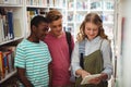 Happy school kids using digital tablet in library Royalty Free Stock Photo