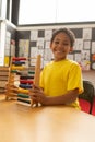 Happy schoolboy with abacus looking at camera in a classroom