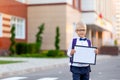 A happy schoolboy boy with blond glasses and a backpack stands at the school and holds a sign with a white sheet. Day of knowledge