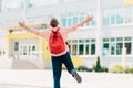 Happy schoolboy boy, in glasses with a backpack, runs to school with pleasure, schoolboy boy on the background of the school Royalty Free Stock Photo