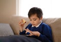 Happy schoolboy eating red apple while playing game online with friend on tablet,Kid using internet sending homework to the Royalty Free Stock Photo