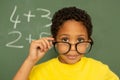 Happy schoolboy looking over spectacle against greenboard in a classroom Royalty Free Stock Photo