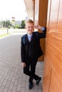 Happy schoolboy stands on the street near the school