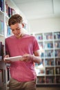 Happy schoolboy using digital tablet in library Royalty Free Stock Photo