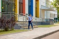 A happy schoolboy in a white shirt, blue tie and backpack descends the steps from the school. Royalty Free Stock Photo