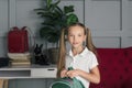 Happy schoolchild in the classroom with big backpack