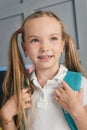 Happy schoolchild in the classroom with big backpack