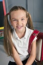 Happy schoolchild in the classroom with big backpack