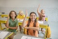 Happy schoolchildren raising their hands wanting to answer Royalty Free Stock Photo