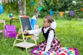 Happy schoolgirl child kid girl sitting on grass and writing on