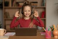 Happy Schoolgirl Gesturing OK To Laptop Making Video Call Indoor