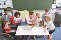 Happy schoolgirl looking at the camera while his classmates and her teacher are arround a table Royalty Free Stock Photo