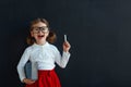 Happy schoolgirl preschool girl with book near school blackboard Royalty Free Stock Photo