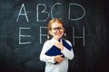 Happy schoolgirl preschool girl with book near school blackboard Royalty Free Stock Photo