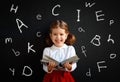 Happy schoolgirl preschool girl with book near school blackboard Royalty Free Stock Photo