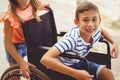 Happy schoolgirl pushing a boy on wheelchair Royalty Free Stock Photo