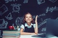 Happy schoolgirl raising hand sitting at laptop during online lesson. Distant School Learning. Royalty Free Stock Photo