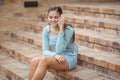 Happy schoolgirl sitting on staircase and talking mobile phone