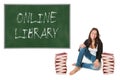 Happy schoolgirl between two huge piles of books in front of a chalkboard Royalty Free Stock Photo