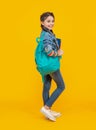 Happy schoolgirl yellow background, education. Teenage girl carrying backpack. School education