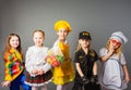 Happy schoolgirls in costumes of different professions isolated on grey background.