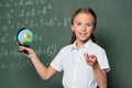 happy schoolkid with small globe pointing