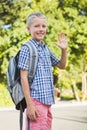 Happy schoolkid waving hand in campus