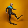 Happy scuba diver diving man going to the side against bright orange studio wall background Royalty Free Stock Photo