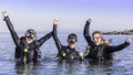 Happy scuba divers in the sea with their arms in the air