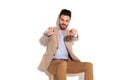 Happy seated businessman pointing fingers